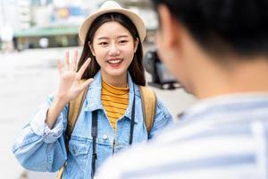 Smiling beautiful Asian woman tourist travel vlogger say hi to camera in the city photo