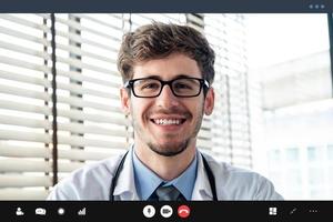 joven médico sonriendo a la cámara mientras realiza una videollamada con el paciente en línea, conceptos de servicio de consulta médica domiciliaria foto