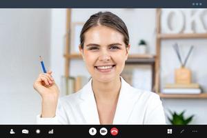 Smiling Caucasian woman in formal business suit looking at camera while making video call, work from home and online interview concepts photo