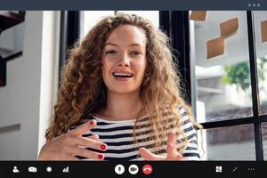 Happy pretty Caucasian woman smiling and  talking at the camera while making video call at home photo