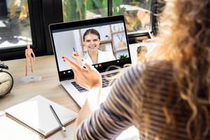 Smiling happy Caucasian woman in business attire working on video conference call with colleague using laptop computer at home in the time of pandemic photo