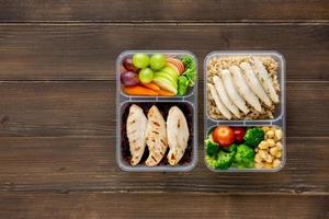 Nutrient rich healthy low fat food in takeaway meal box sets on wood background top view with copy space photo