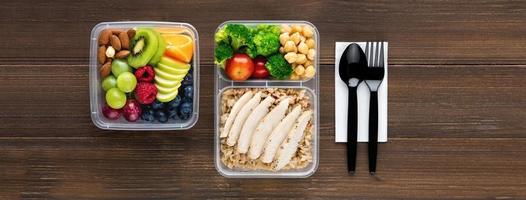 Top view of wholesome nutrient rich food set in take away boxes with spoon and fork on wood table banner background photo