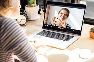 Smiling happy Caucasian woman chatting with female friend via online video call meeting using laptop computer in the time of pandemic, work from home concept photo