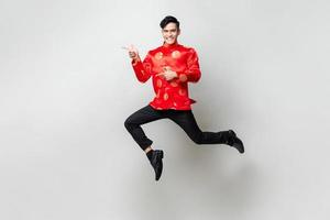 Portrait of smiling handsome Asian man in traditional chinese attire smiling and pointing hands to empty space aside in light gray isolated studio background photo