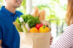 Groceries delivered to customer at home by a delivery man, for online food service concept photo