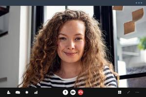 feliz mujer caucásica sonriendo a la cámara mientras hace una videollamada en casa foto