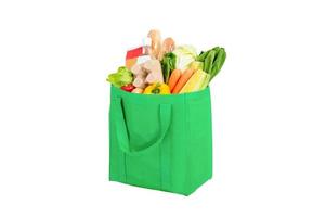 Green reusable shopping bag full of vegetables and groceries isolated on white background photo