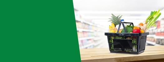 Shopping basket full of groceries on wood counter in supermarket background banner with copy space for text photo