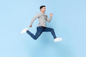 Smiling handsome man jumping in light blue color isolated studio background photo