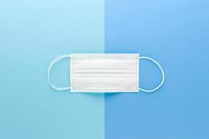 New clean white medical face mask isolated on light blue paper backgrounds top view photo