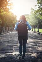 Rear view of young attractive woman tourist with backpack coming to shoot photo at ancient phanom rung temple in thailand.