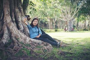 Young hipster woman taking selfie on her phone while sitting at green park. photo