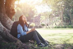 Young hipster woman sitting at green park. Enjoy with nature surrounding. photo
