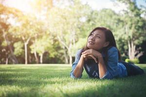 Charming smiling young hipster woman lying on green grass. photo
