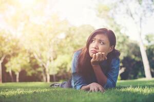 Charming smiling young hipster woman lying on green grass. photo