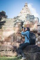 joven y atractiva mujer fotógrafa turista con mochila que viene a tomar fotos en el antiguo templo de peldaño fantasma en tailandia.