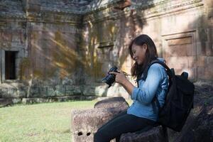 joven y atractiva mujer fotógrafa turista con mochila que viene a tomar fotos en el antiguo templo de peldaño fantasma en tailandia.