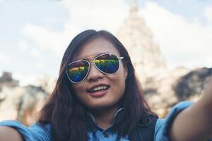 joven mujer atractiva tomando selfie en su teléfono mientras viaja en el templo de phnom peldaño en tailandia. foto