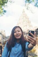 Young attractive woman taking selfie on her phone while travling at phnom rung temple in thailand. photo