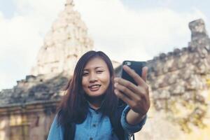 Young attractive woman taking selfie on her phone while travling at phnom rung temple in thailand. photo