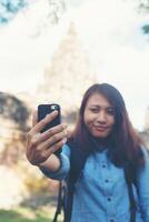 Young attractive woman taking selfie on her phone while travling at phnom rung temple in thailand. photo