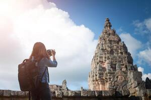 Young attractive woman photographer tourist with backpack coming to shoot photo at ancient phanom rung temple in thailand.