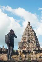Rear view of young attractive woman tourist with backpack coming to shoot photo at ancient phanom rung temple in thailand.