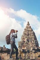 Young attractive woman photographer tourist with backpack coming to shoot photo at ancient phanom rung temple in thailand.