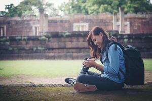 Young attractive woman photographer tourist with backpack coming to shoot photo at ancient phanom rung temple in thailand.