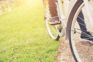 primer plano de una joven hipster sosteniendo su pie en el pedal de la bicicleta. foto