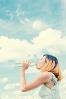 Women lifestyle concept  young beautiful woman with white dress drinking water at summer green park. photo