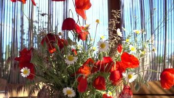Blumenstrauß aus Mohn und Gänseblümchen auf dem Tisch video