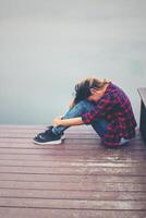 mujer hipster triste sentada en el muelle con tristeza. foto