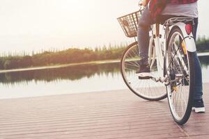 primer plano de una joven hipster sosteniendo su pie en el pedal de la bicicleta. foto