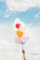 Woman Lifestyle concept  woman hand holding a bunch of colored balloons with blue sky. photo