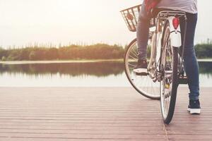 primer plano de una joven hipster sosteniendo su pie en el pedal de la bicicleta. foto