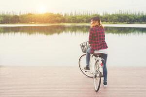 parte trasera de una joven hipster en bicicleta en un muelle, relajándose y disfrutando de las vacaciones de verano. foto