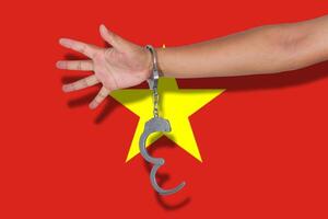 handcuffs with hand on Vietnam flag photo