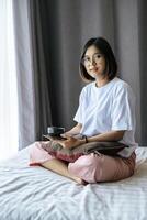 A girl sitting and drinking coffee on the bedroom. photo