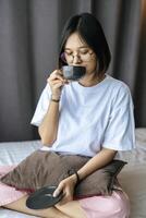 una chica sentada y tomando café en el dormitorio. foto