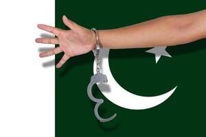 handcuffs with hand on Pakistan flag photo