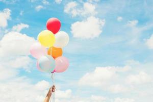 Woman Lifestyle concept  woman hand holding a bunch of colored balloons with blue sky. photo