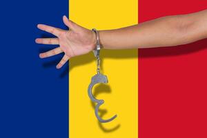 handcuffs with hand on Romania flag photo