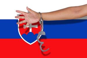 handcuffs with hand on Slovakia flag photo