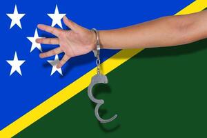 handcuffs with hand on Solomon Islands flag photo