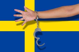 handcuffs with hand on Sweden flag photo