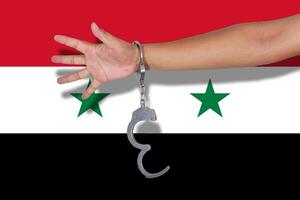 handcuffs with hand on Syria flag photo