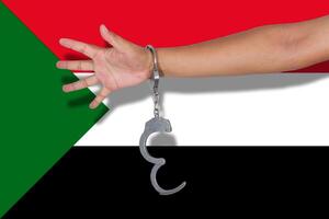 handcuffs with hand on Sudan flag photo