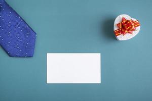 Gift box with tie and card on a turquoise background. Holiday gifts closeup with copy space photo